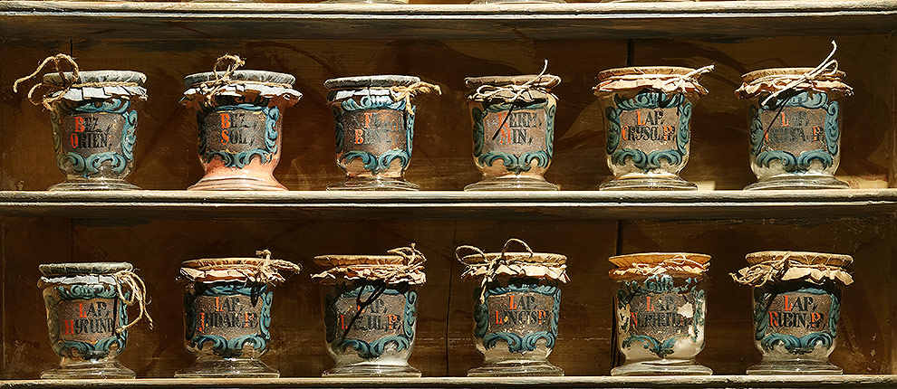Teure Kostbarkeiten und Raritäten wurden im Pretiosenschrank aufbewahrt und durch vergittertes Glas geschützt. Zwölf Medizinfläschchen aus Glas aus dem 17. Jh., gefüllt mit dem Originalinhalt.